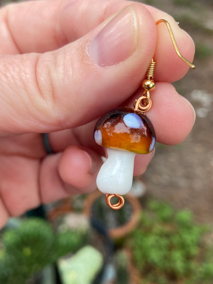 closeup of brown and white glass mushroom earring