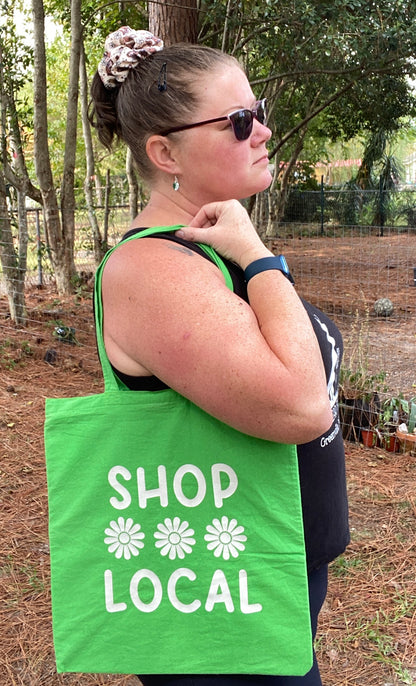 woman holding green and white shop local tote bag