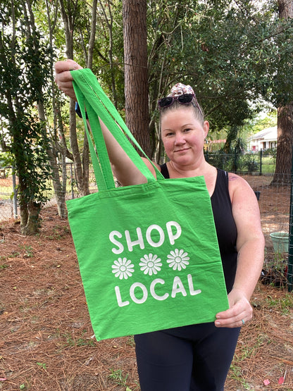 woman holding green and white shop local tote bag