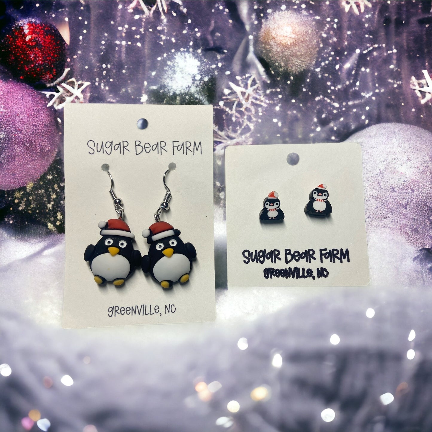 two Pair of penguin earrings on a winter background