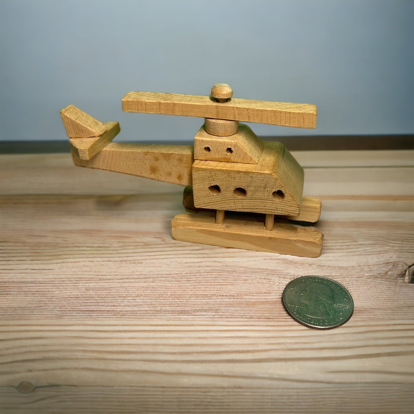 wooden helicopter next to a quarter