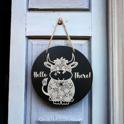 black door sign with a cow and reads "hello there"