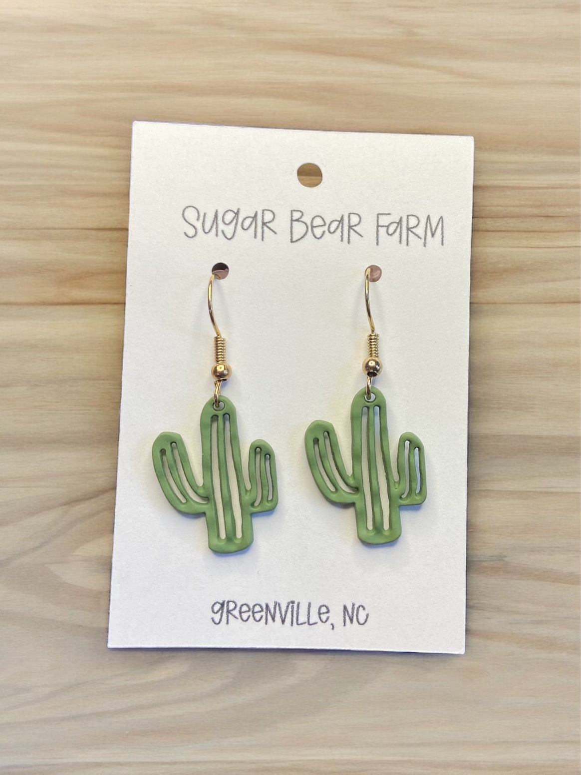 green cactus earrings on wood