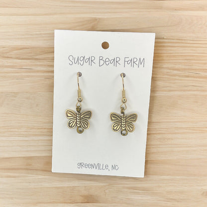 gold colored butterfly earrings on wood