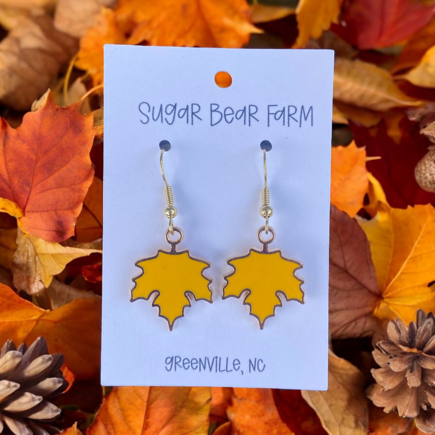 pair of yellow leaf earrings on a leaf background