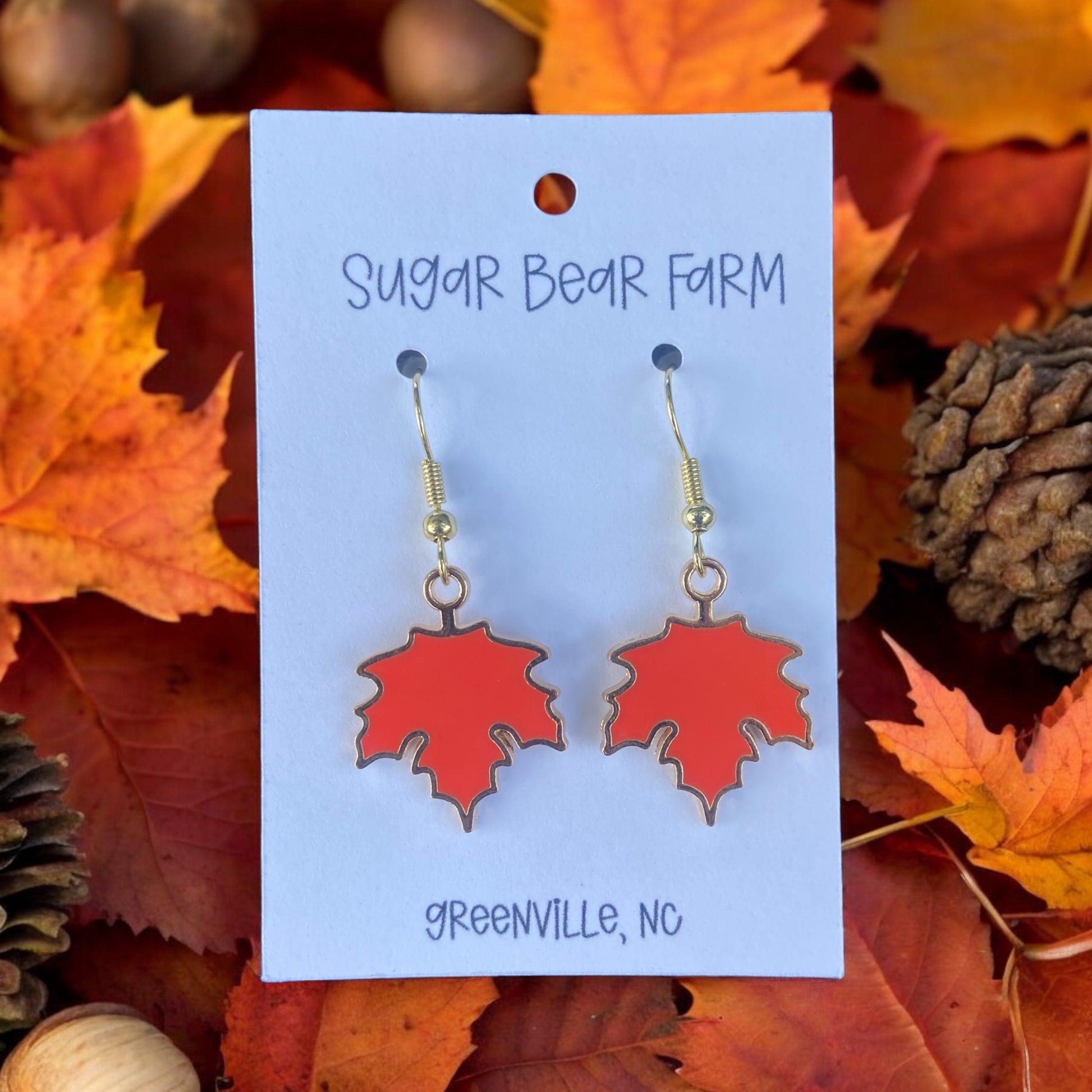 pair of orange leaf earrings on a leaf background