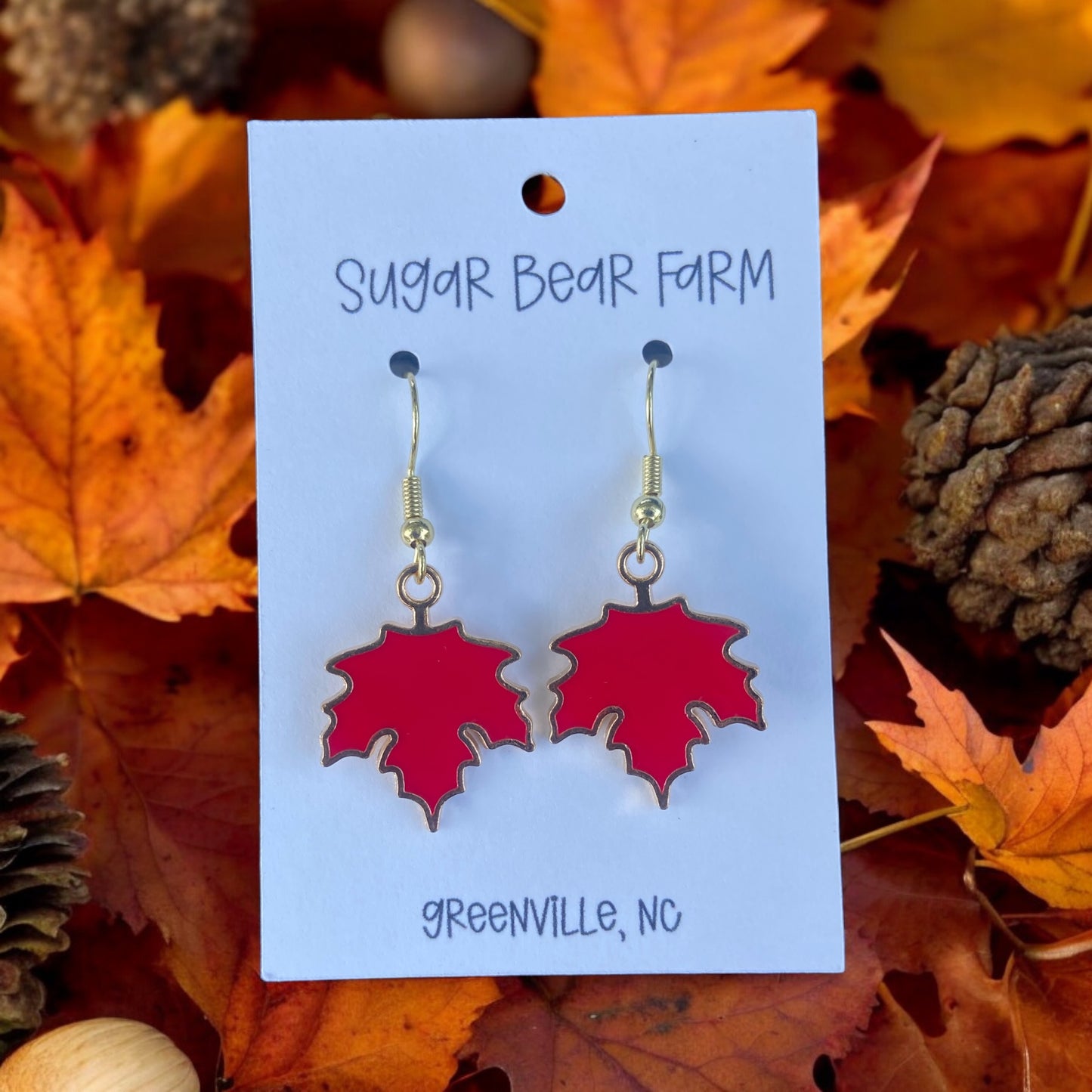 pair of red leaf earrings on a leaf background