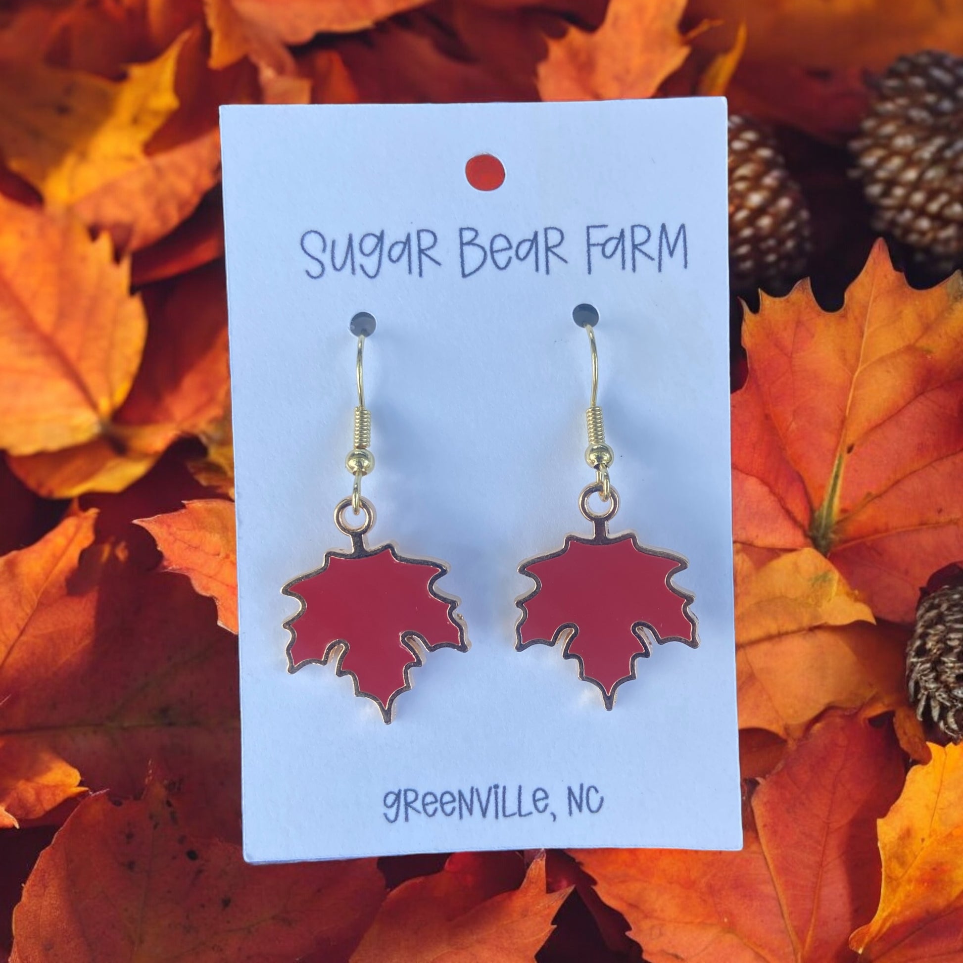 pair of red leaf earrings on a leaf background