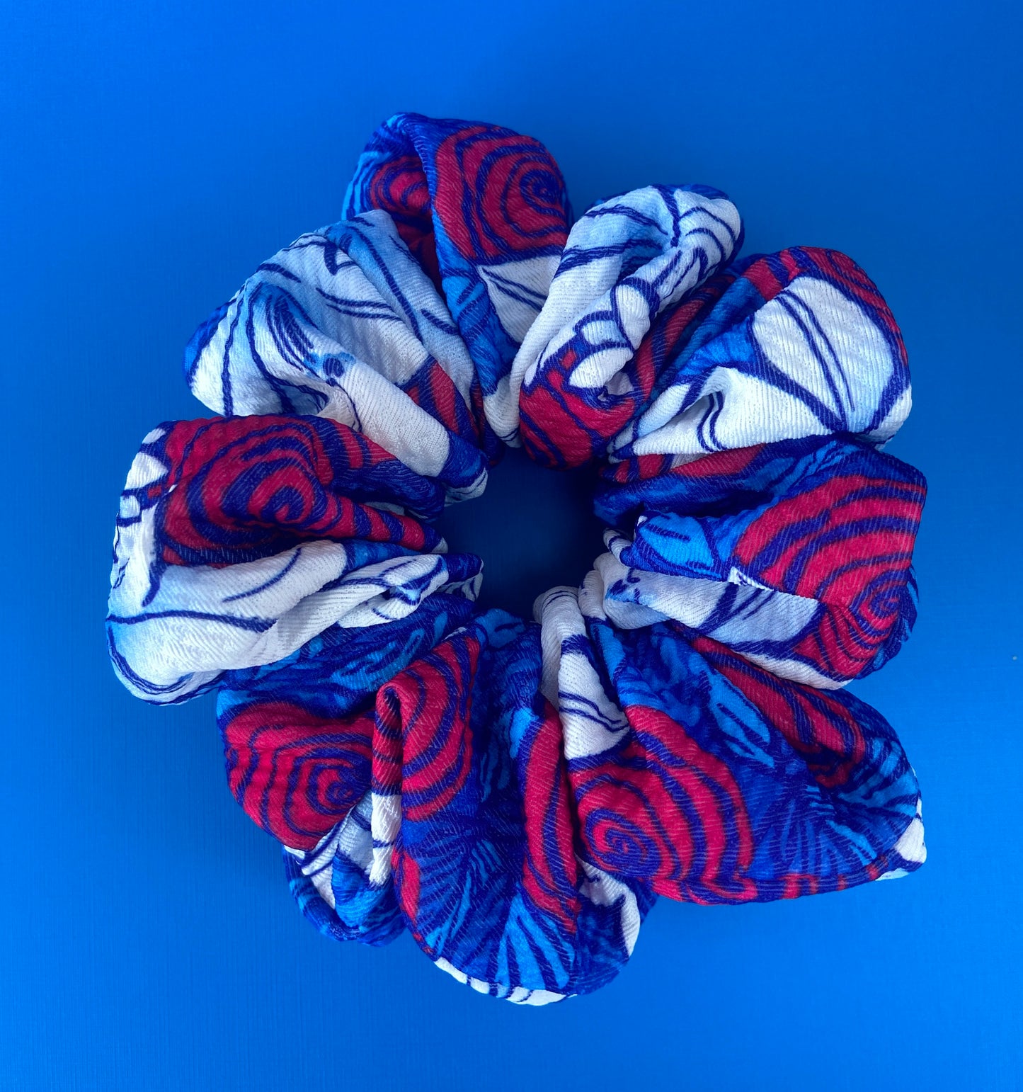 red, white, and blue floral scrunchie on blue background