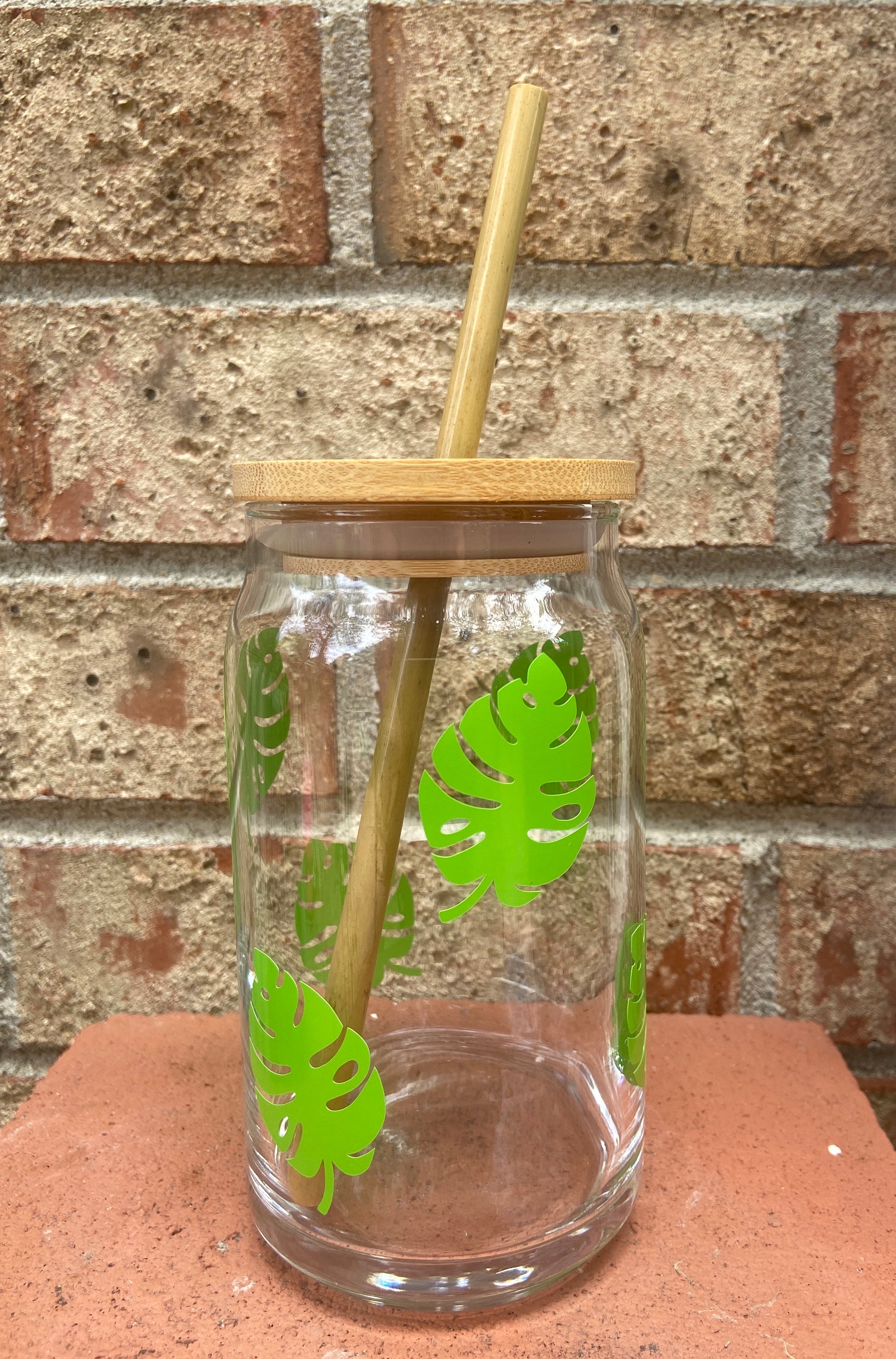 Beer glass with green monstera leaves and bamboo lid