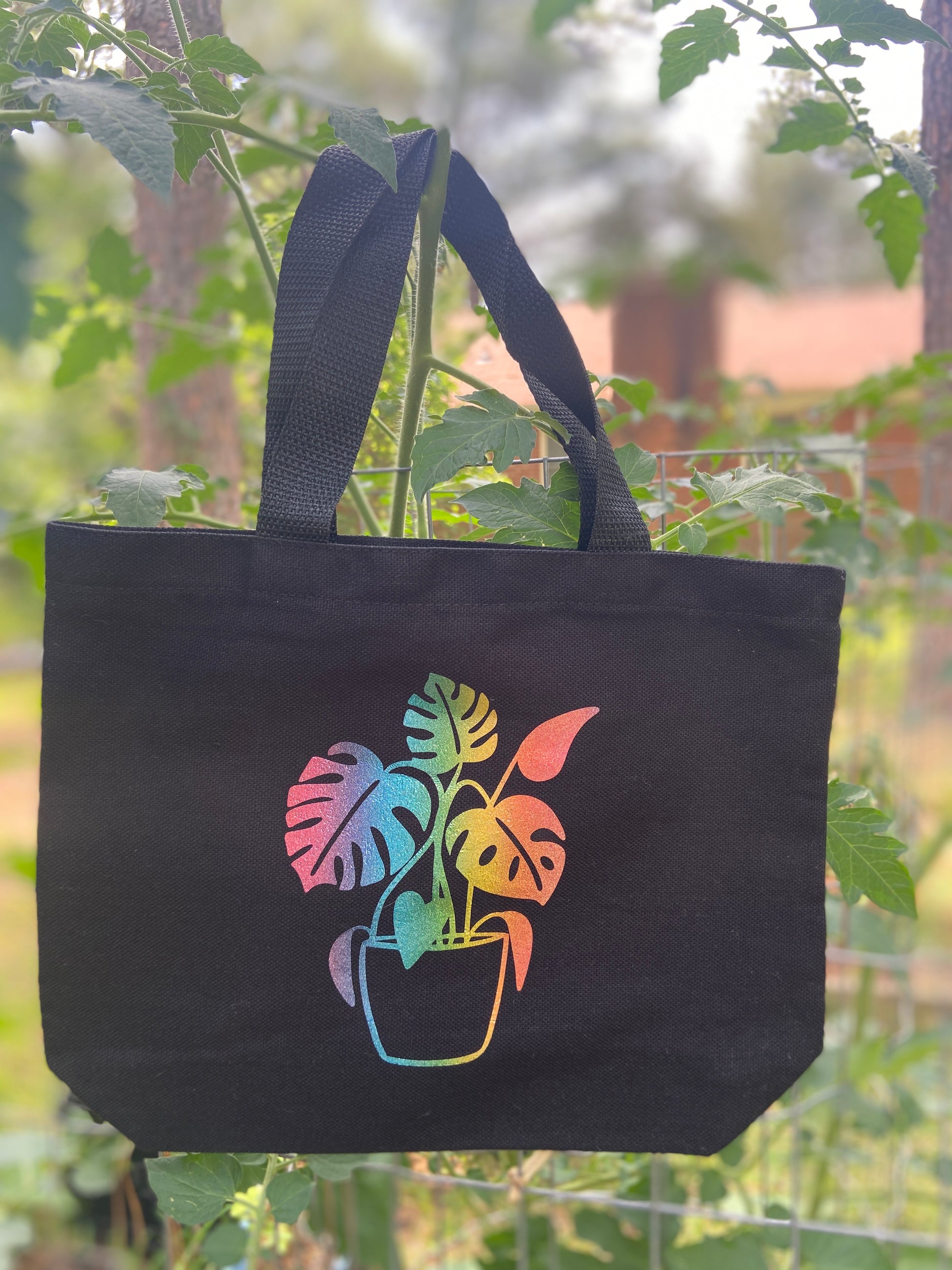 shimmer rainbow monstera on a black tote bag