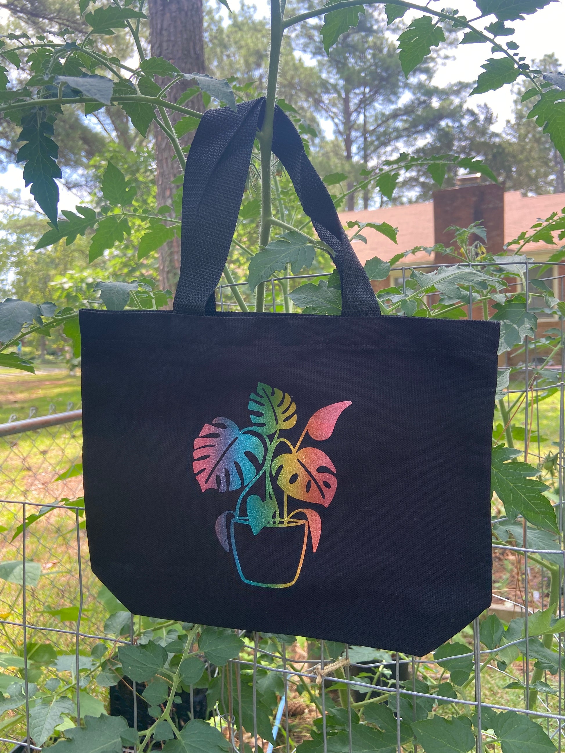 shimmer rainbow monstera on a black tote bag